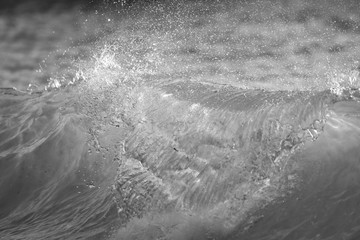 Water splashing. Crystal clear sea water. Sea waves break on the shore after a storm. Toned black and white image