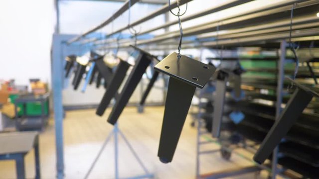 Freshly powder coated metal parts hang to dry in factory