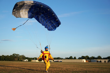 Landing of a parachuter against the background of forests and buildings. A man in a bright yellow...