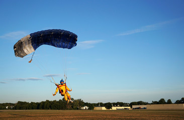 Skydiver under a small blue canopy of a parachute is landing on airfield, speed and close-up
