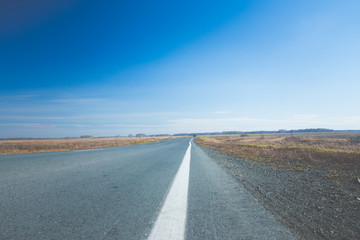Empty road through the autumn fields. Toned image.