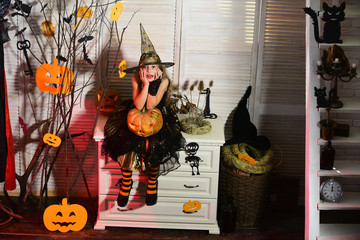 Little witch with Halloween decor. Girl with troubled face