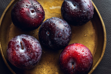 Fresh ripe plums on a plate top view