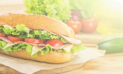 Sandwich with ham and vegetables on wooden board