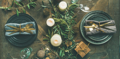 Christmas or New Years celebration party table setting. Flat-lay of plates, golden cutlery, festive...