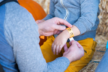 Man putting a paper bracelet on childs hand.