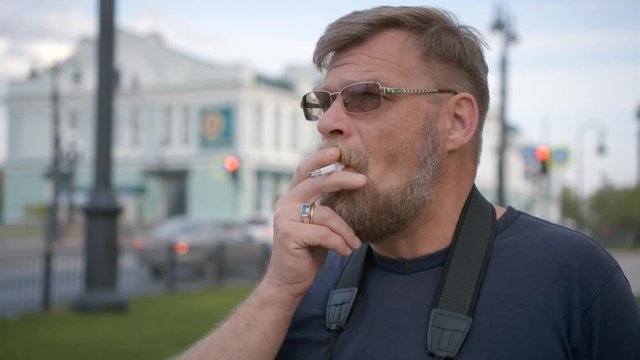 Close-up of a smoking man in the street.