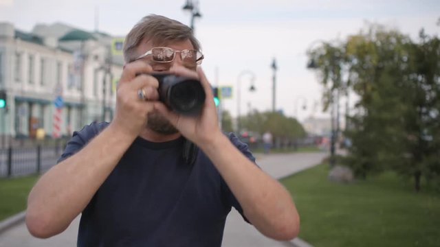 Adult man takes photos with a camera on a city street.