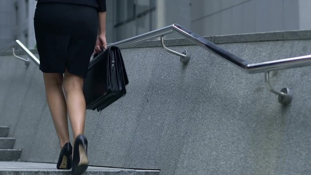 Young woman confidently walking up corporate ladder, diligence and hardwork