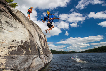 Kids jumping off cliffs while on a canoe trip