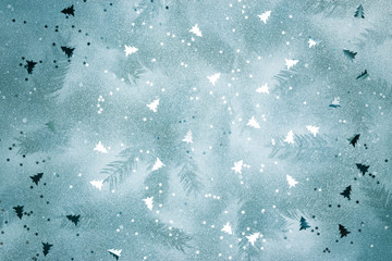 christmas tree branches imprints on frozen winter background with glossy silver confetti