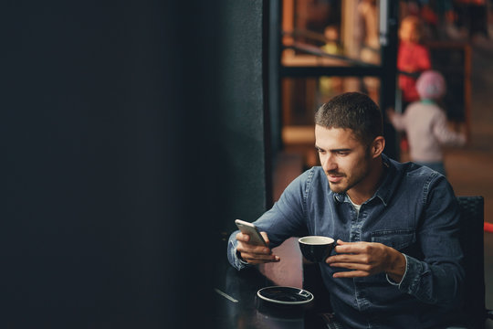man using phone inside a restaurant - Powered by Adobe