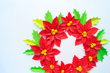 Paper flower poinsettia and leaves of holly