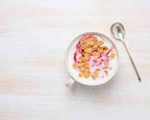 Fototapeta na wymiar greek yogurt with jam and muesli in white bowl on white wooden table, top view, copy space