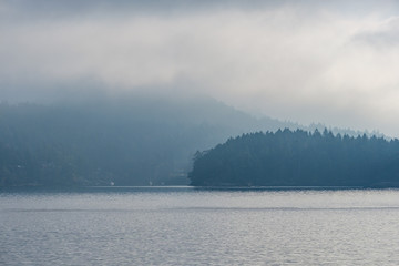 islands by the sea covered in cloud in the morning with a hint of light through the cloud