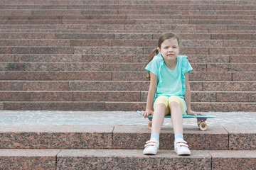 on the steps a girl sits on a skateboard