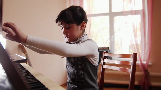 A little girl opens up a piano cover and starts playing