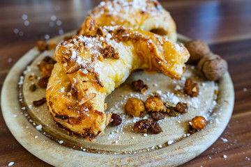 Mandelhörnchen mit Puderzucker und Nüssen auf einem Holzbrett