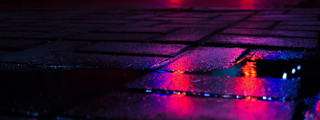 Background of wet asphalt with neon light. Blurred background, night lights of a big city, reflection, puddles. Dark neon bokeh.