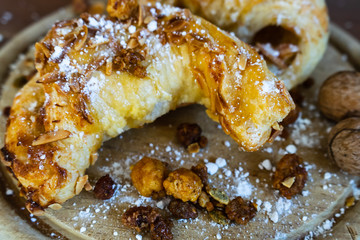 Mandelhörnchen mit Puderzucker und Nüssen auf einem Holzbrett