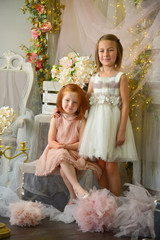 Fototapeta na wymiar Girls on the queen throne with flowers in rich fairytale interior studio shot