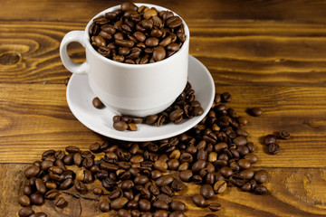 Coffee beans in white cup on wooden table