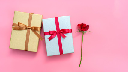 Red rose and gift box on a pink background.