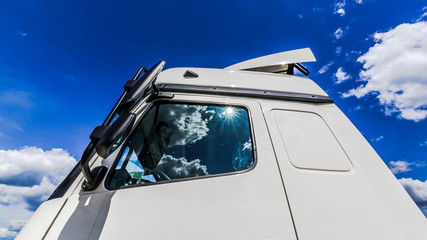 Fototapeta premium The sun and clouds reflected in the glass of the truck
