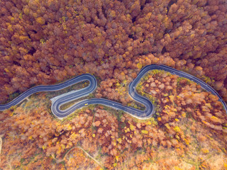 Winding road from high mountain pass, in autumn season.