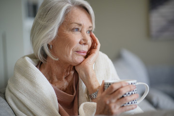  Cosy ooking senior woman at home with hot drink