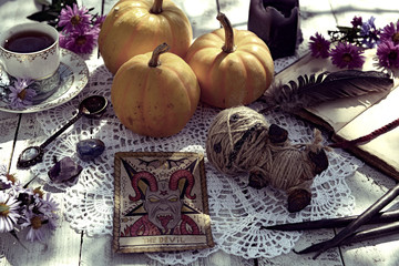 Still life with voodoo doll, the Devil tarot card, cup of tea and pumpkins. Mystic background with ritual objects, occult, fortune telling and halloween concept