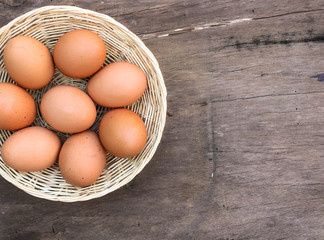 Many eggs are in a basket placed on a wooden floor.   