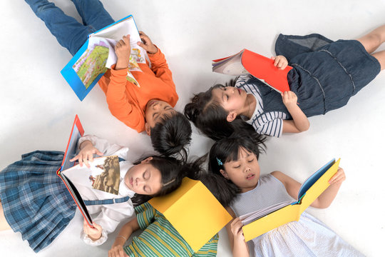 Kids Reading Book Laying On The White Floor ,head To Head, In A Circle Group, Preschool Library,Kindergarten School Education Concept