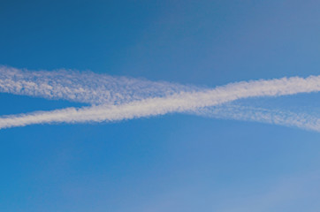 Condensation trails of planes in the sky. Sunny autumn blue sky. Aviation. Travel concept