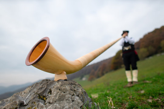 Alpine horn. A man plays in an alpine valley