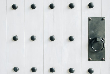 The close up of white old vintage wooden door, metal door holder.