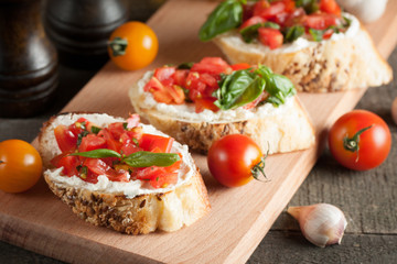 Italian tomato and cheese bruschetta. Tapas, antipasti with chopped vegetables, herbs and oil on grilled ciabatta and baguette bread.