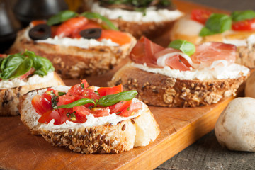 Italian tomato and cheese bruschetta. Tapas, antipasti with chopped vegetables, herbs and oil on grilled ciabatta and baguette bread.