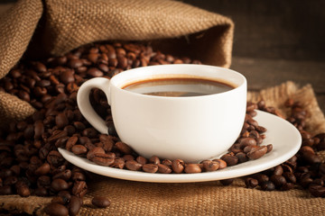 Coffee cup and beans on a rustic background. Coffee Espresso and a piece of cake with a curl. Cup of Coffee and coffee beans on table.
