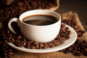 Coffee cup and beans on a rustic background. Coffee Espresso and a piece of cake with a curl. Cup of Coffee and coffee beans on table.