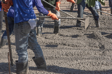 Workers using a wooden spatula for cement after Pouring ready-mixed concrete on steel reinforcement...