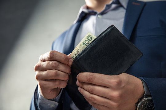 Elegant man in suit pulls out his money from wallet. Conception of money management.