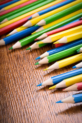 Fototapeta premium Different colored pencils on the brown wooden table background .Top view .Close up .Color .Pencil.Set