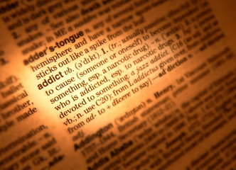 CLOSE UP OF DICTIONARY PAGE SHOWING DEFINITION OF THE WORD ADDICT