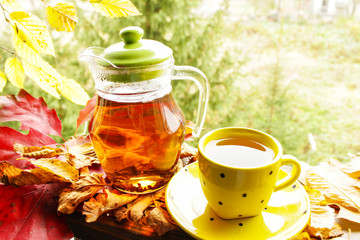 Hot tea and autumn leaves on vintage wood background. Warm sunny day of the golden autumn 