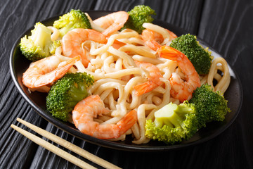 Asian style udon noodles with shrimp, broccoli and soy sauce close-up on a plate. horizontal