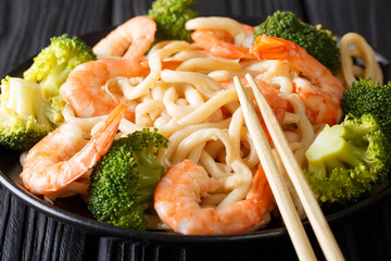 Udon noodles with shrimps and broccoli closeup on a plate on the table. horizontal
