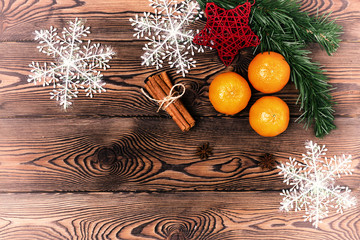 Christmas background - old wood, fir branches, pine cone, snowflakes and tangerines, New Year's decor. Flat lay, copy space