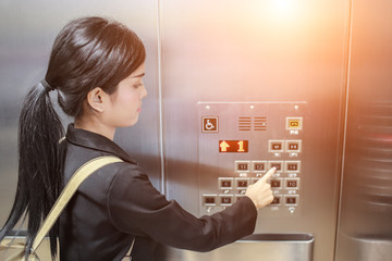 businesswomen pressing elevator button with sun light effect.