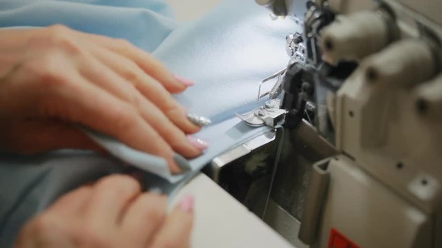 Woman's hands sewing an overlock at sewing machine. Overlock stitch on sewing machine. Automatic sewing machine. Close-up